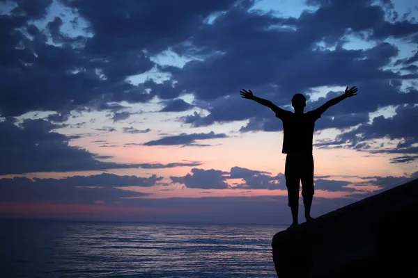 Silhouette guy placed hands in sides on breakwater in evening ne — Stock Photo, Image