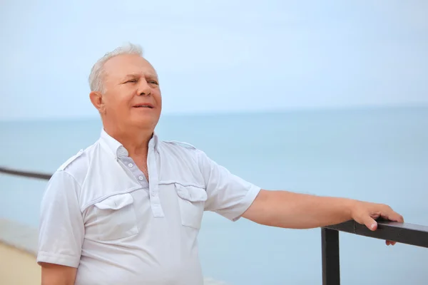 Tankeväckande senior på verandan nära seacoast, ser på avstånd — Stockfoto