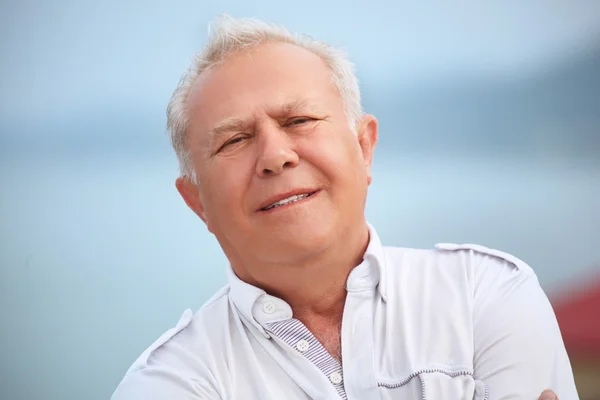 Usměvavý starší nedaleko mořského pobřeží, sklon hlavu stranou — Stock fotografie