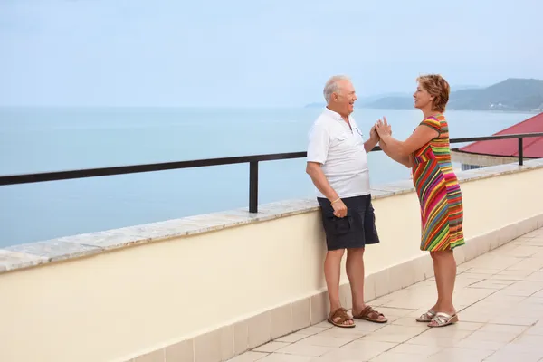 Smiling elderly married couple on veranda near seacoast, play ha — Stock Photo, Image