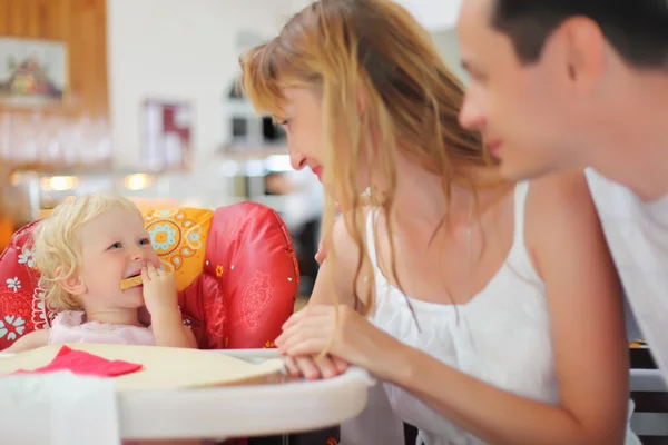 Familia feliz con la niña rubia comiendo pan — Foto de Stock