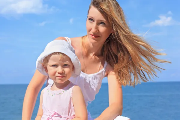 Beautiful woman with little girl in white hat near sea — Stock Photo, Image