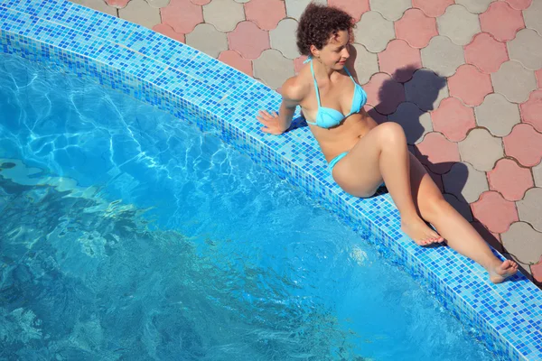 Сексуальная женщина, сидящая у бассейна на курорте, расслабляется — стоковое фото