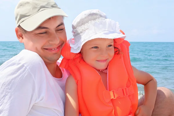 Giovane con bambina in giubbotto di salvataggio arancione sulla spiaggia — Foto Stock