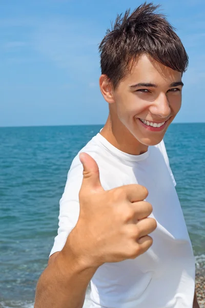 Mosolygós tinédzser fiú ellen tengeri mutatja — Stock Fotó