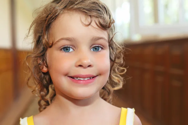 Красива усміхнена маленька дівчинка з кучерявим волоссям в коридорі — стокове фото