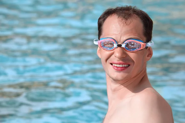 Joven sonriente en gafas de deporte acuático nadando en la piscina —  Fotos de Stock