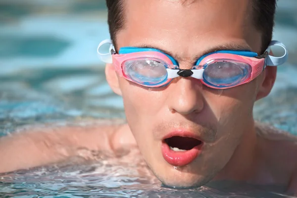 Joven en gafas de deporte acuático nadando en la piscina, tomando aliento —  Fotos de Stock