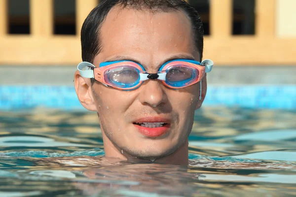 Молодой человек в водно-спортивных очках плавает в бассейне — стоковое фото