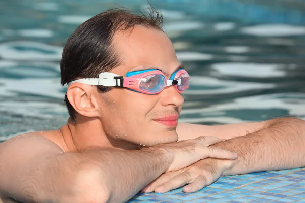 Молодой человек в водно-спортивных очках плавает в бассейне, возле выступа — стоковое фото