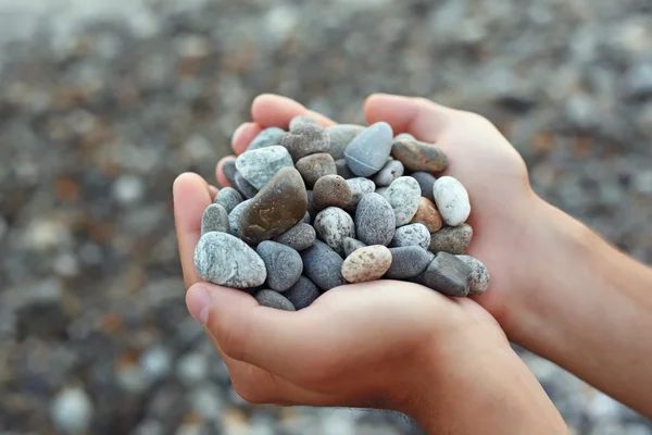 Handful of stones in hands, Against stones — Stock Photo, Image