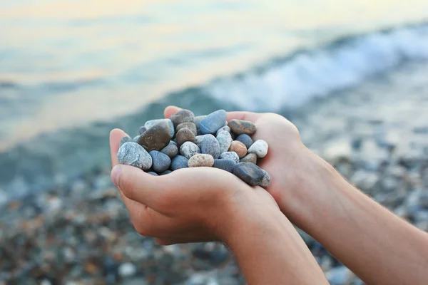 Manciata di pietre in mano, contro pietre e mare — Foto Stock