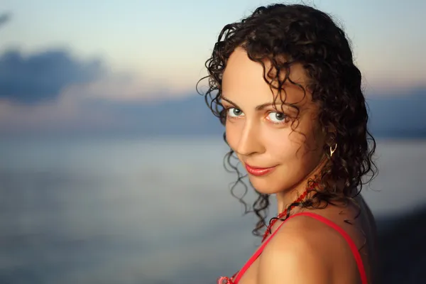 Curly beautiful young woman near sea in evening, Steadfastly loo — Stock Photo, Image