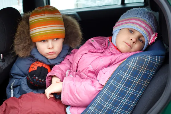 Το θλιβερό αγόρι με το κοριτσάκι, χειμωνιάτικα ρούχα στο αυτοκίνητο. — Φωτογραφία Αρχείου