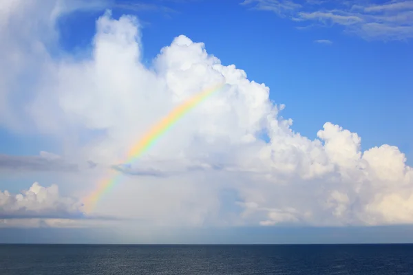 Witte grote wolken en multi gekleurde regenboog over zee in afterno — Stockfoto