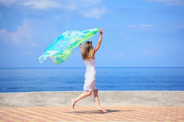 Красивая молодая женщина с тканями, бегущими по набережной — стоковое фото