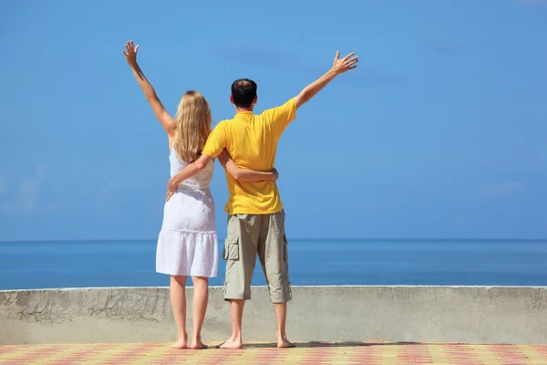 Young man and beautiful woman on quay lifted hands upwards — Stock Photo, Image