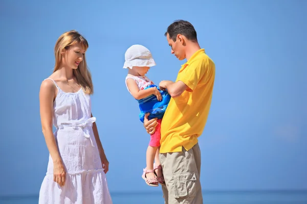 Счастливая семья с маленькой девочкой в белой шляпе на фоне моря — стоковое фото