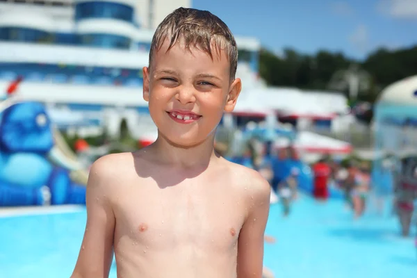 Niño mojado sonriente cerca de la piscina en el parque acuático de un complejo entretenido —  Fotos de Stock