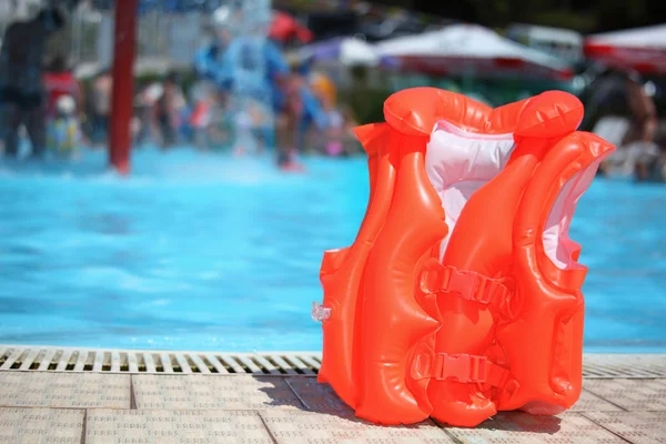 Chaleco salvavidas naranja cerca de la piscina en aquapark —  Fotos de Stock