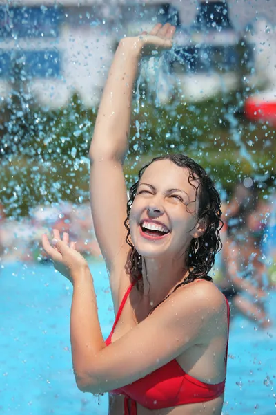 Lächelnde schöne Frau badet im Pool unter Wasserspritzern, lif — Stockfoto