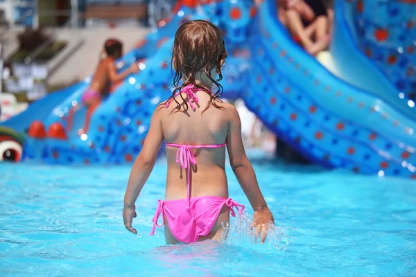 Μικρό κορίτσι στέκεται στην πισίνα στο aquapark, στέκεται πίσω — Φωτογραφία Αρχείου