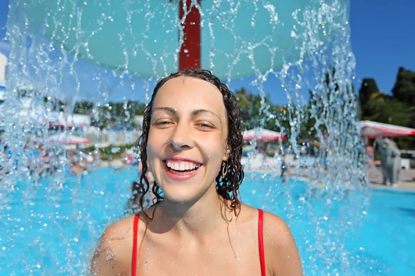 Mooie vrouw glimlachend baadt in zwembad onder water spatten, und — Stockfoto