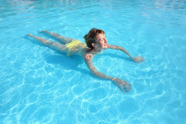 Young beautiful woman swimming in yellow bikini in paddling pool — Stock Photo, Image
