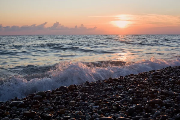 日没、石の多い浜辺の波と海の海岸 — ストック写真