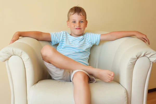 Boy freely sitting with magnificent easy chair in cosy room — Stock Photo, Image