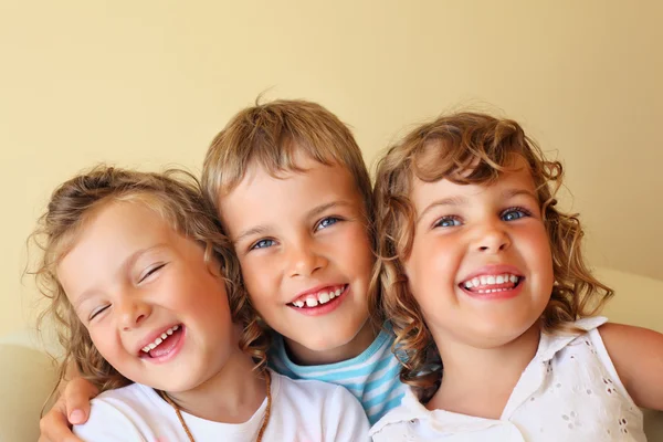 Uśmiechnięte dzieci trzy razem w przytulnym, dziewczyna po lewej stronie zamknięte oczy — Zdjęcie stockowe