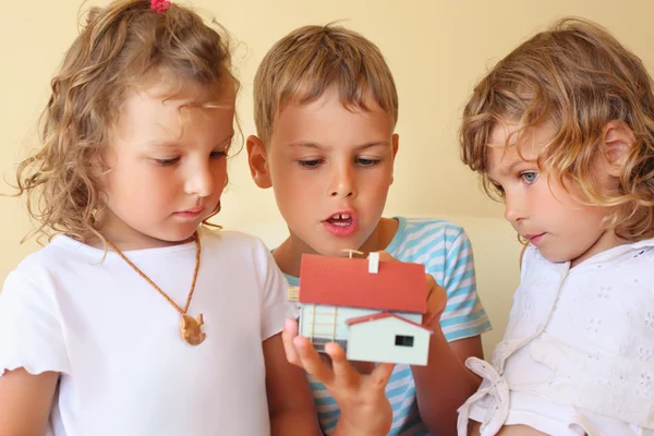 Los niños tres juntos que llevan en las manos el modelo de casa en confortable —  Fotos de Stock
