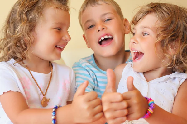 Crianças sorridentes três juntos em sala acolhedora mostra — Fotografia de Stock