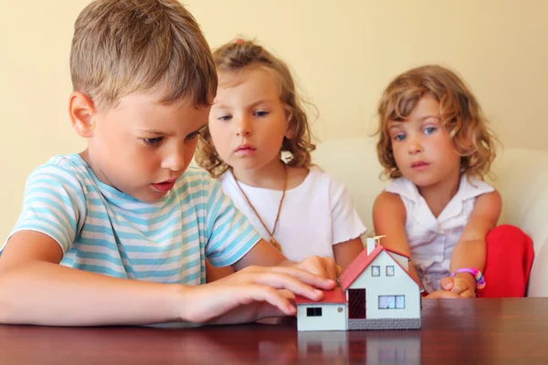 Crianças três juntos olhando para o modelo de casa de pé em ta — Fotografia de Stock