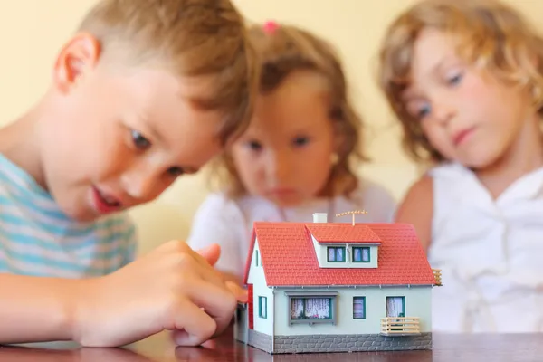 Crianças três juntos olhando para o modelo de casa de pé em ta — Fotografia de Stock