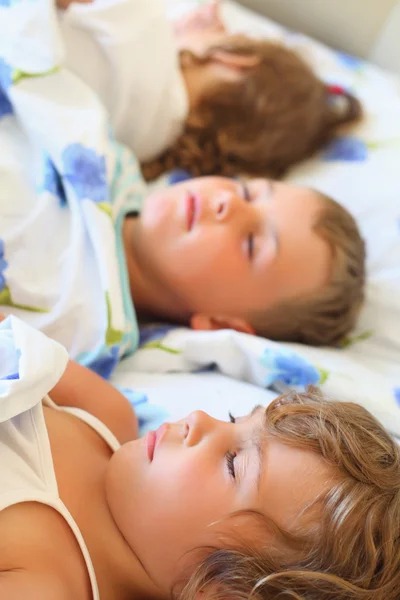 Дети втроем спят на кровати в уютной комнате, лежащей на б — стоковое фото