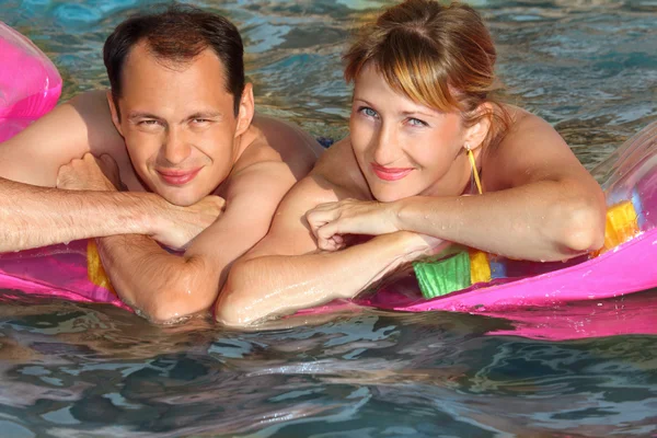 年轻的男人和好女人躺在游泳池充气床垫 — 图库照片