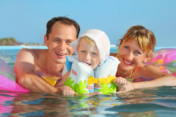 Happy family with little girl in white hat and lifejacket bathin — Stock Photo, Image