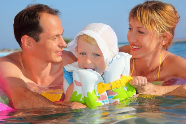 Happy family with little girl in white hat and lifejacket bathin — Stock Photo, Image