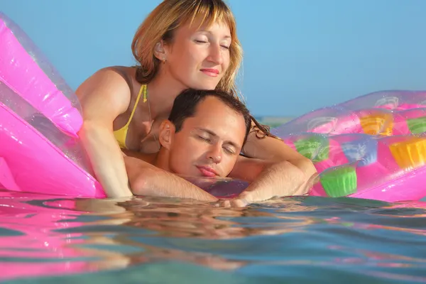 Hombre joven y mujeres agradables duermen en un colchón inflable en la piscina —  Fotos de Stock