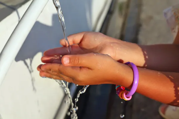 Washing of hands of little girl by water from pipe in street — Stock Photo, Image