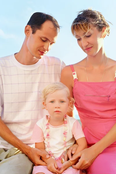 Ευτυχισμένη οικογένεια με μικρό κορίτσι στην παραλία, τους γονείς που κοιτάζουν στο κορίτσι — Φωτογραφία Αρχείου