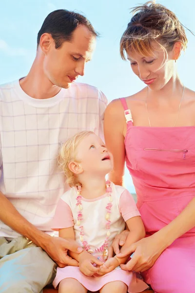 Счастливая семья с маленькой девочкой у моря, глядя друг против друга — стоковое фото