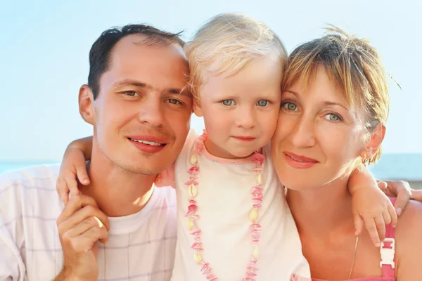 Happy family with little girl near to sea, concerning with heads — Stock Photo, Image
