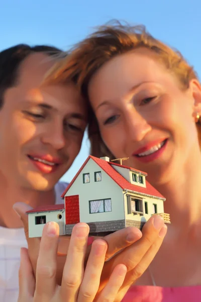 Młoda kobieta i mężczyzna, trzymając w rękach model dom z garażem — Zdjęcie stockowe
