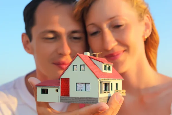 Young woman and man keeping in hands model of house with garage — Stock Photo, Image