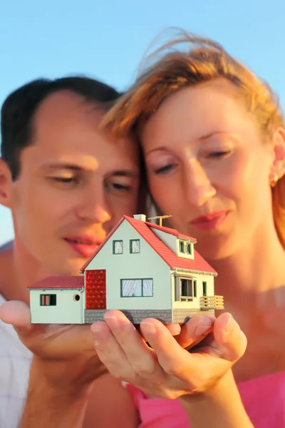 Молодая женщина и мужчина держат в руках макет дома — стоковое фото