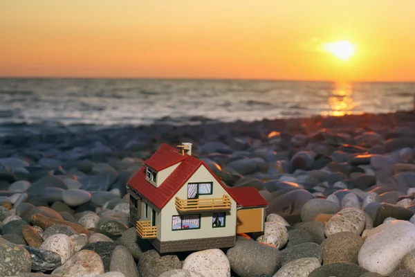 Model of house with garage on stony beach in evening — Stock Photo, Image