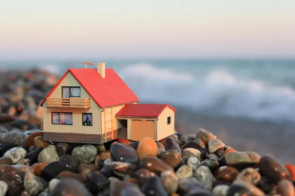 Modell eines Hauses mit Garage am steinigen Strand am Abend — Stockfoto