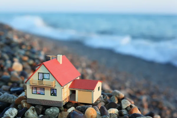 Модель дома с гаражом на каменистом пляже вечером — стоковое фото